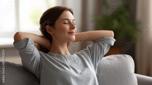 Free Download Young woman relaxing on sofa with hands behind head, indicating relaxed lifestyle and comfort at home, casual downtime in residential living room setting, peaceful rest moment on c - GFXLoad
