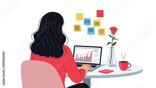 Back view of a young woman with dark wavy hair working on a laptop at a desk with sticky notes and a single red rose in a glass vase.