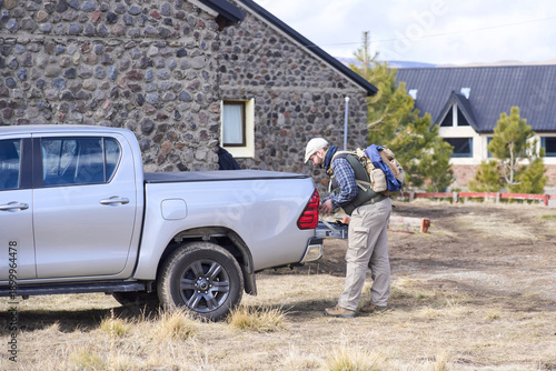 A young Hispanic traveler loads the trunk of his pickup truck, an ideal vehicle for an adventurous road trip.