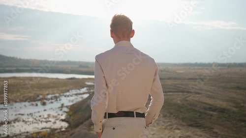 Wallpaper Mural Young man standing on a hill overlooking a river. Concept of admiring nature. Torontodigital.ca