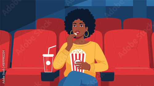Smiling African American woman with curly hair eating popcorn and drinking a soda while enjoying a movie at a cinema, depicting leisure and entertainment.