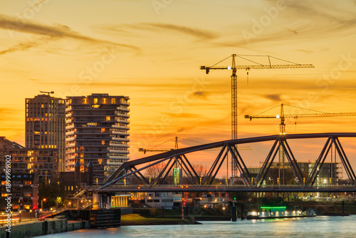 Sunset view of apartments, railway bridge and construction cranes in the Dutch city of Nijmegen