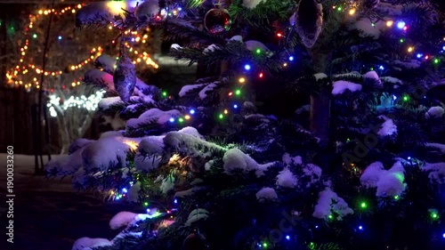 Wallpaper Mural Close-up of a snow-covered Christmas tree branch at night. Colorful LED lights shine, illuminating ornaments and fresh snow. Multicolored bokeh fills the background. A magical festive atmosphere.  Torontodigital.ca