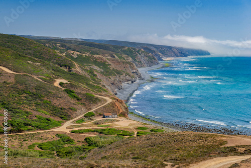 view on a  beach  in atlantic ocean and hill on the coast with a dirty road at Aljezur in the Algarve region in Portugal