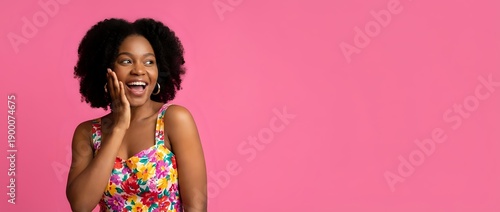 Excited African American woman with curly hair talking on smartphone against bright pink background, expressing joy and surprise during phone conversation.