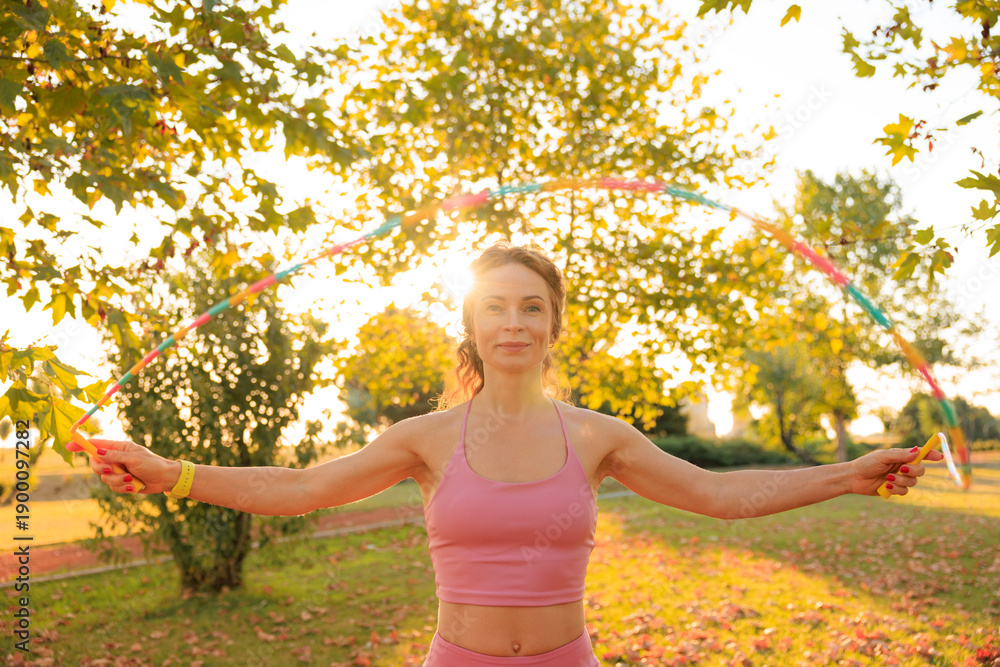 Fototapeta premium Fit sportswoman jump rope outdoors in spring park