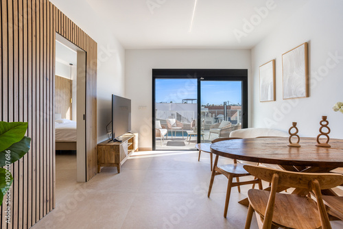 Modern minimalist apartment interior with natural light and access to furnished balcony
