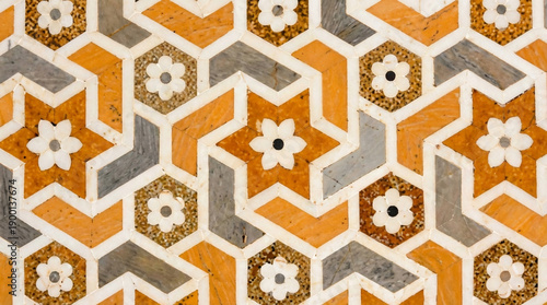 Intricate geometric mosaic pattern with star and floral motifs in orange, white, and gray marble