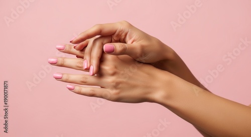 Woman's hands with pink manicured nails on pink background beauty and skincare concept with focus on nail health and hygiene