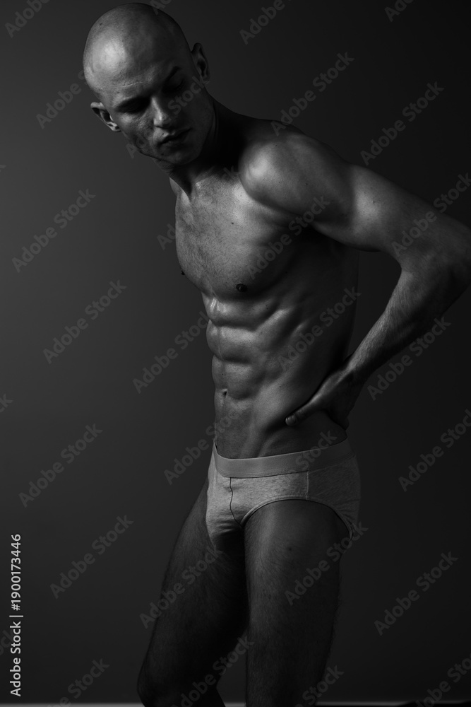 Naklejka premium Athletic man posing in a black and white photograph, highlighting his toned physique and strong silhouette. An artistic representation of strength and confidence.