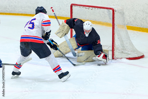 A hockey player attacks an opponent's goalkeeper