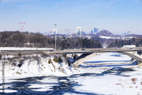 High angle winter view of bridge over the partly frozen Chaudière river, with the Pierre-Laporte and Quebec bridges in the background, Lévis, Québec, Canada