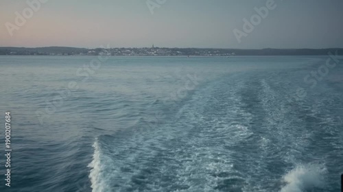 Looking off the back of a moving boat at sunrise