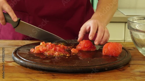 Woman cooking sauce with fresh tomato at the kitchen