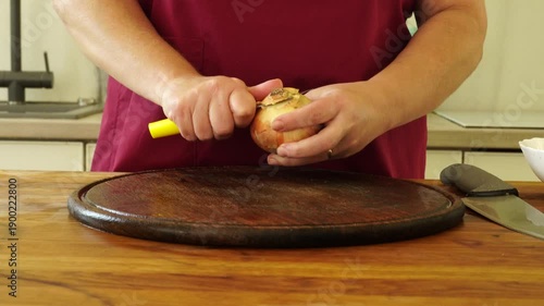 Woman is peeling and cutting onions for cooking
