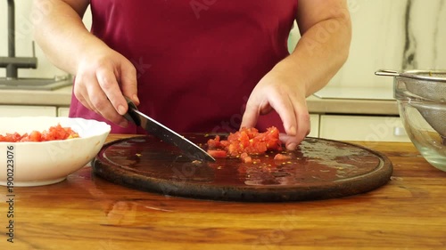 Woman cooking sauce with fresh tomato at the kitchen