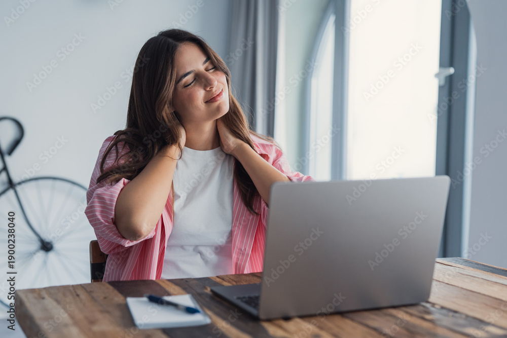 Obraz premium Tired woman feels neck pain, rubs tensed muscles seated at table, suffers from chronic shoulder back ache after long laptop usage, sedentary work, poor posture, health problems, fibromyalgia concept