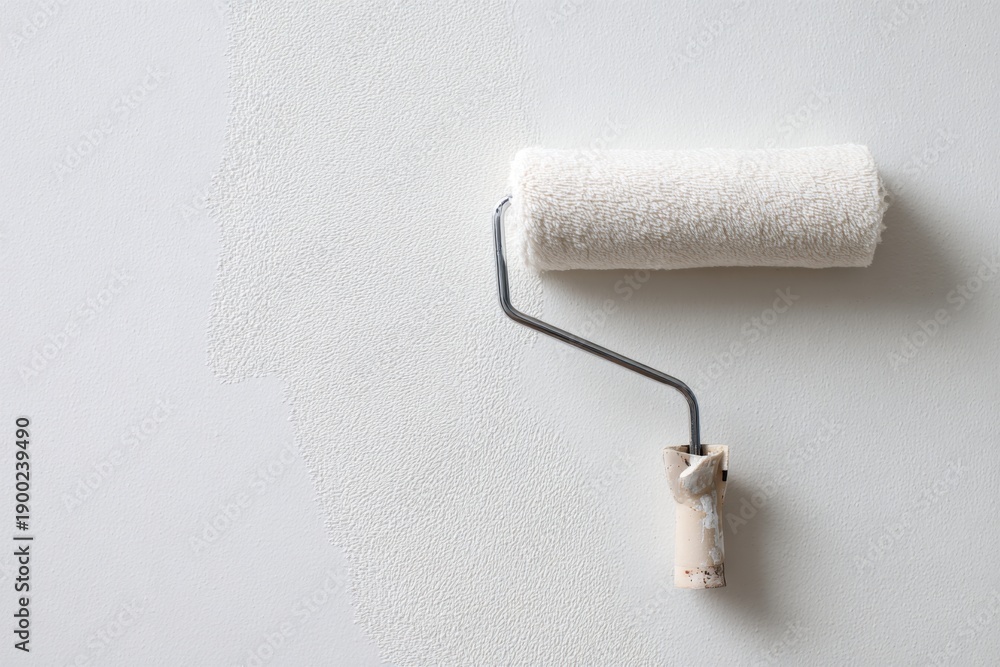 Obraz premium paint roller with white fabric on a wall