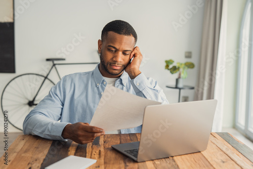 Foto African student guy sit at desk hold papers tasks having difficulties with test,