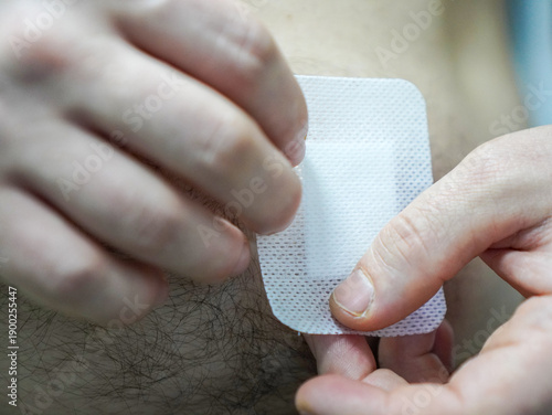 Bild auf Leinwand A man puts a Band-Aid on a knife wound on his stomach, received through negligence
