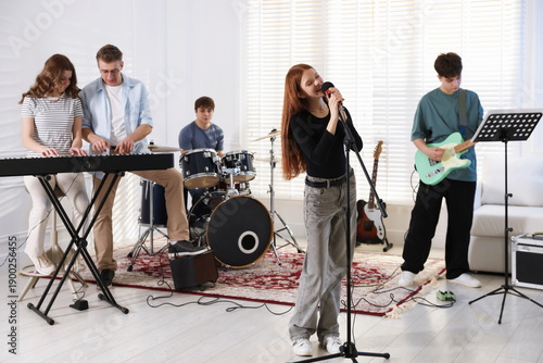 Fotografie Teenage band practicing their performance with music teacher indoors