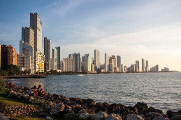 A panoramic cityscape showing famous American skylines with tall skyscrapers along the water under a clear sky