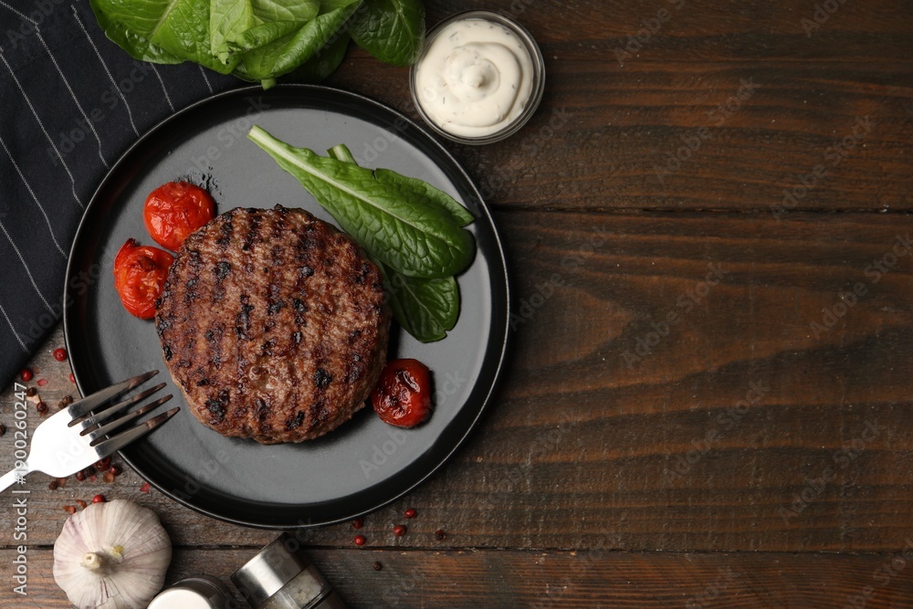 Obraz premium Delicious grilled meat patty, tomatoes and spinach on wooden table, flat lay. Space for text