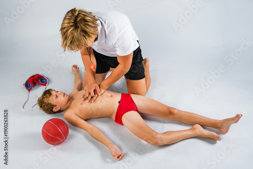 Fényképezés Water polo coach performing lifesaving first aid on an injured young player