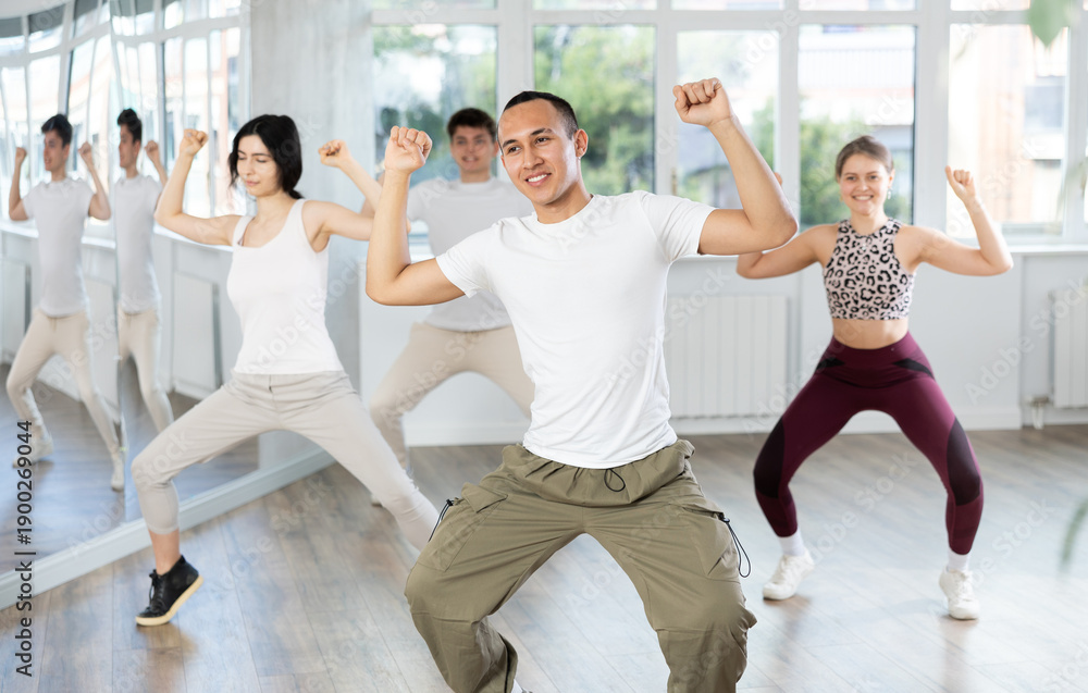 Obraz premium During dance workshop, guy enjoys active dancing, learns new movements, moves synchronously with participants of lesson. Concept of beautiful body through sports, dancing, and active lifestyle