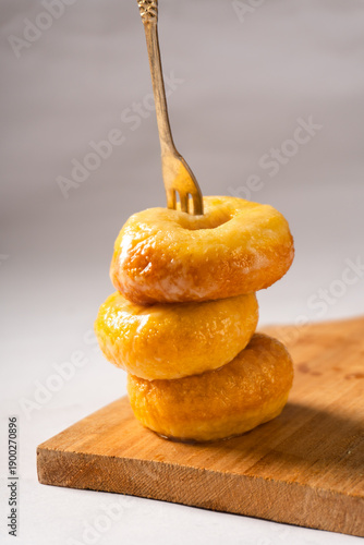 Sugar donut snacks pierced with a fork on a wooden cutting board with a white background.Traditional Indonesian snacks