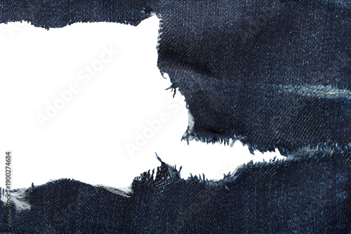 Torn denim fabric with large frayed hole, textured blue background for fashion and advertising