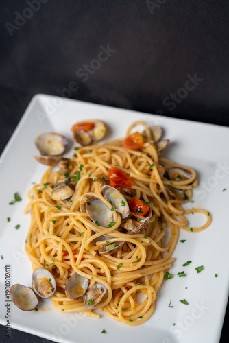 Freshly cooked pasta on black plate with herbs and toppings in elegant food photography