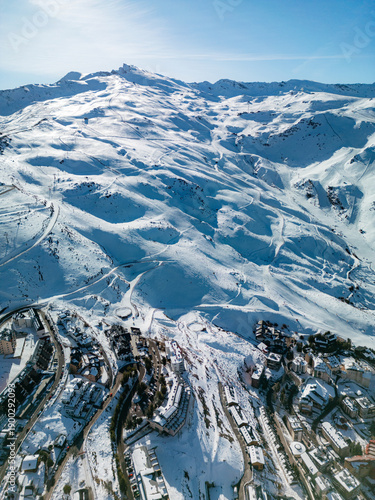 Drone panorama of Sierra Nevada ski resort in Spain, showing snowy slopes, chairlifts and mountain village, ideal background for winter travel, tourism and alpine sports concepts.