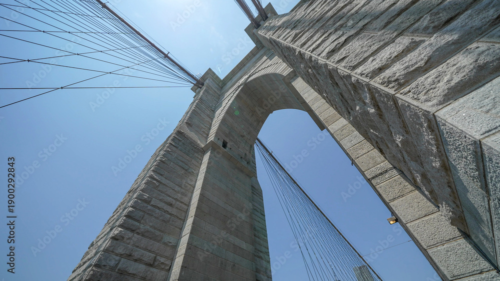 Fototapeta premium Brooklyn Bridge stone pillars captured from below highlighting structural details and grandeur