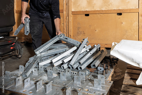 Worker handling galvanised steel frame sections in storage warehouse
