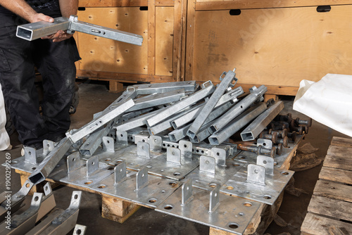 Worker handling galvanised steel frame sections in storage warehouse