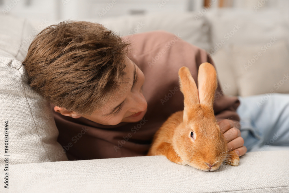 Naklejka premium Happy man with cute bunny on sofa at home