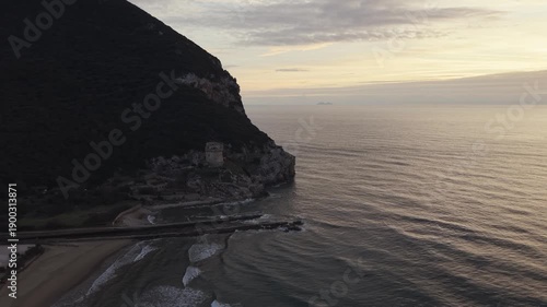 Aerial view of Sabaudia beach and Monte Circeo at sunset, featuring the historic Torre Paola watchtower. Cinematic drone shot of the Lazio coast, sandy dunes, and Mediterranean sea in Italy.