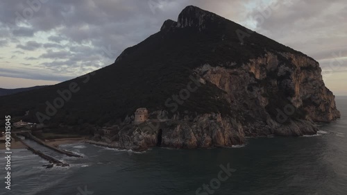 Aerial view of Sabaudia beach and Monte Circeo at sunset, featuring the historic Torre Paola watchtower. Cinematic drone shot of the Lazio coast, sandy dunes, and Mediterranean sea in Italy.