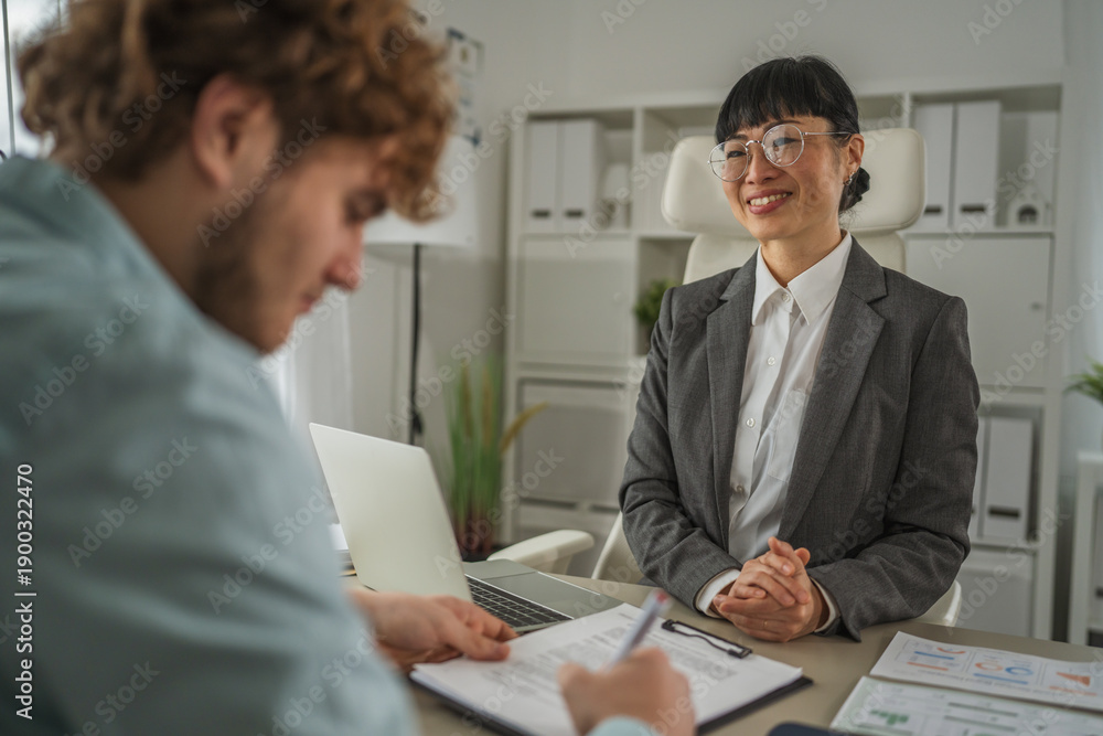 Fototapeta premium Young man signing employment contract with manager