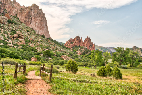 Canvas Print A path leads through a grassy field with a fence on the left side