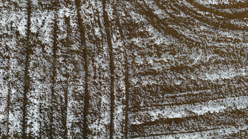 Top down view of tilled soil in a winter field with white snow highlighting the ridges and patterns of the agricultural landscape