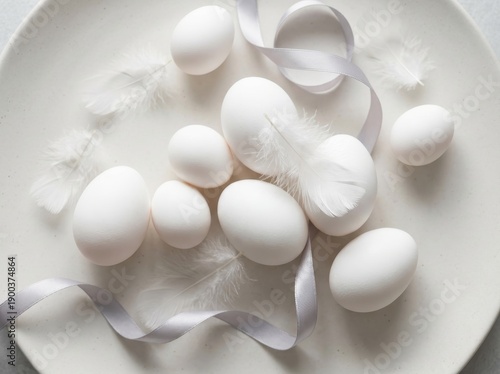 Soft white eggs are artfully arranged on a plate with delicate feathers and a satin ribbon, evoking a sense of spring and celebration.
