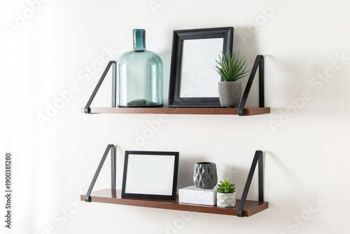 A close-up shot of two shelving units filled with a variety of decoration objects and blank black picture frame mockup