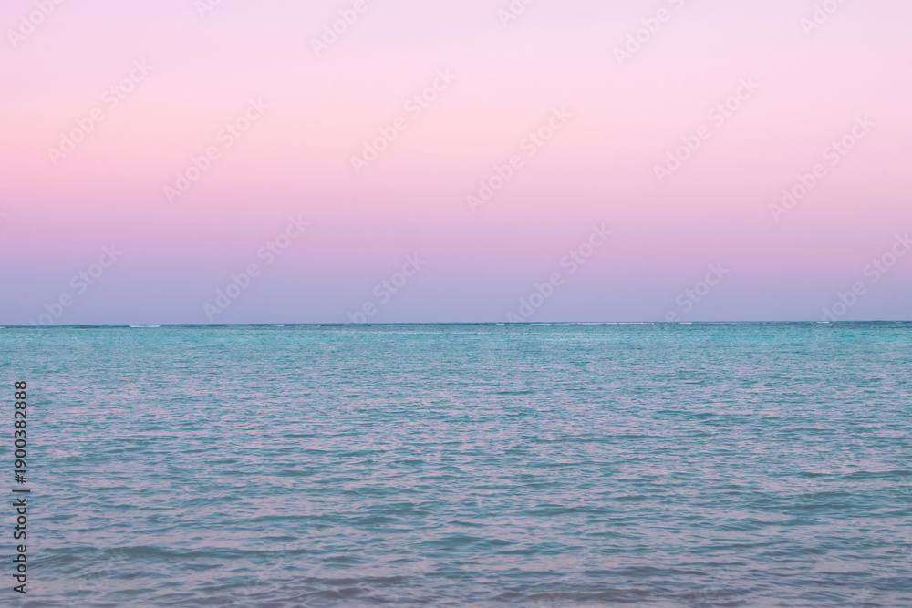 Fototapeta premium Tropical sunset with pink cloudy sky and peaceful water.