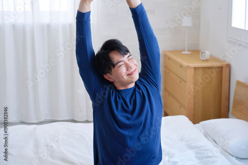 Wallpaper Mural ベッドに座って伸びをする20代男性 Torontodigital.ca