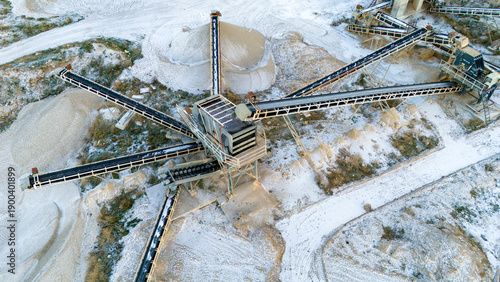 Fotografie Top-down aerial drone view of radial conveyor belts extending from a central stone crushing machine