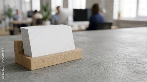 blank white business cards in wooden holder on grey concrete desk in modern office