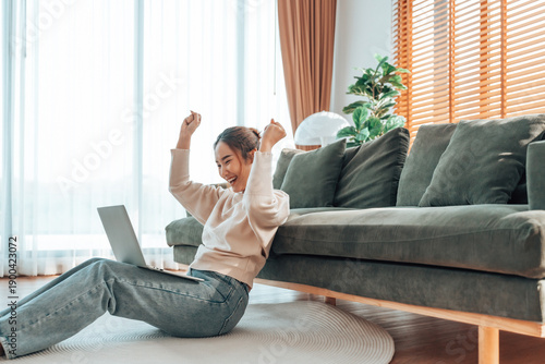 Funny euphoric young asian woman celebrating winning or getting ecommerce shopping offer on computer laptop. Excited happy girl winner looking at notebook celebrating success