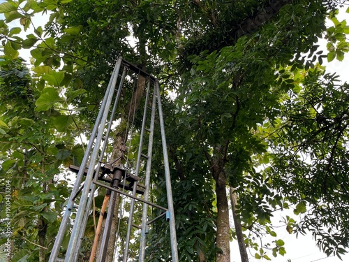 Fotografie Upper section of water well drilling tower viewed from below, highlighting metal framework, height, and industrial function in outdoor setting